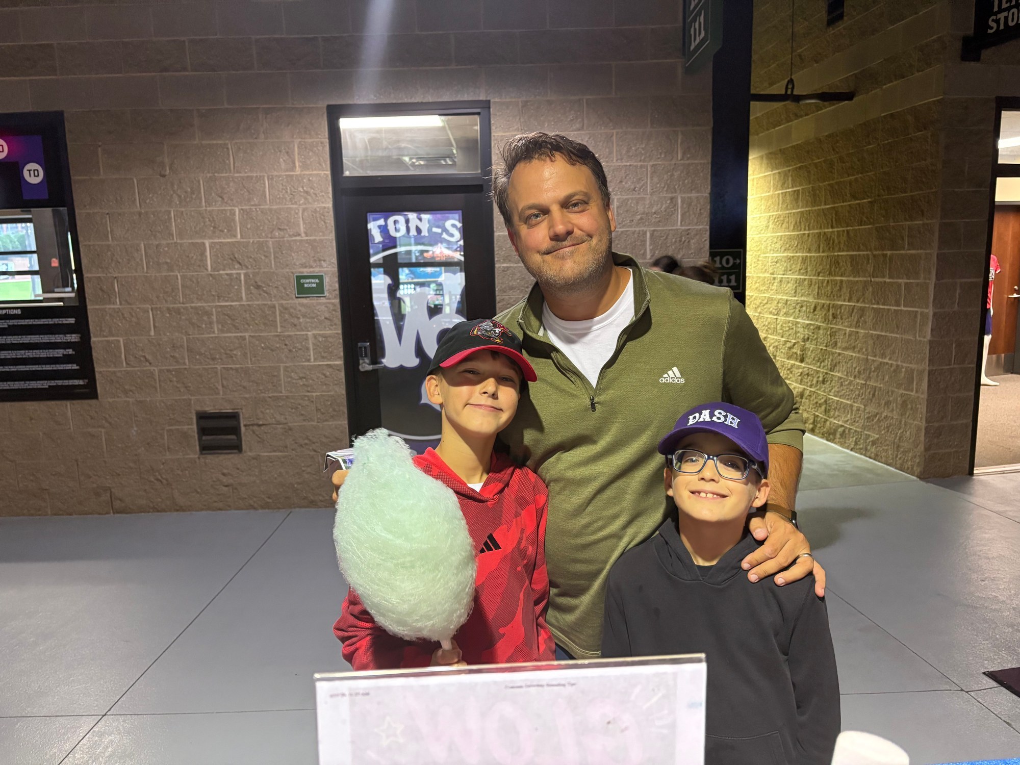 Father and sons enjoying fresh blue cotton candy at a Winston-Salem Dash game