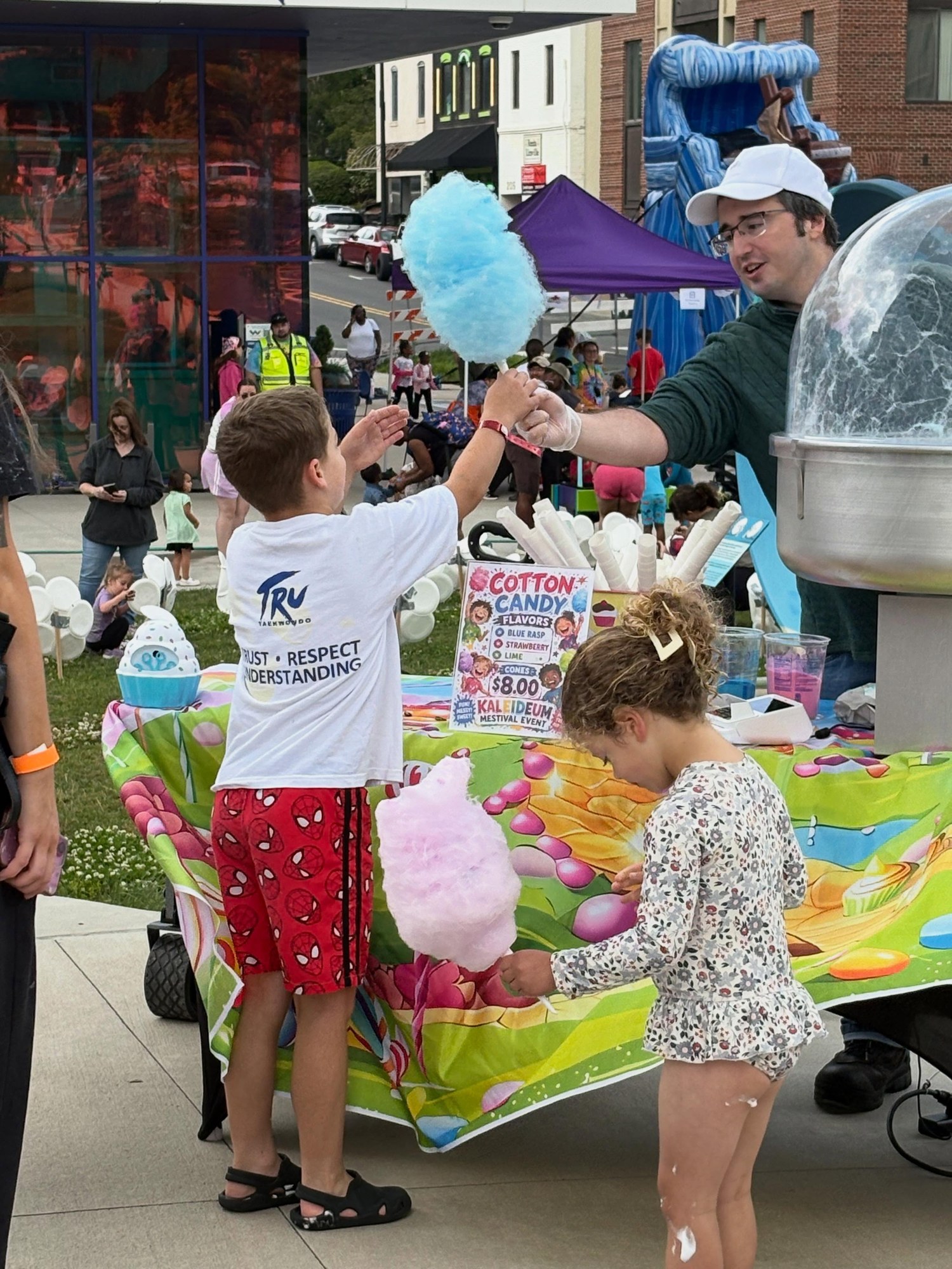 Serving fresh blue and pink cotton candy to children at a community festival